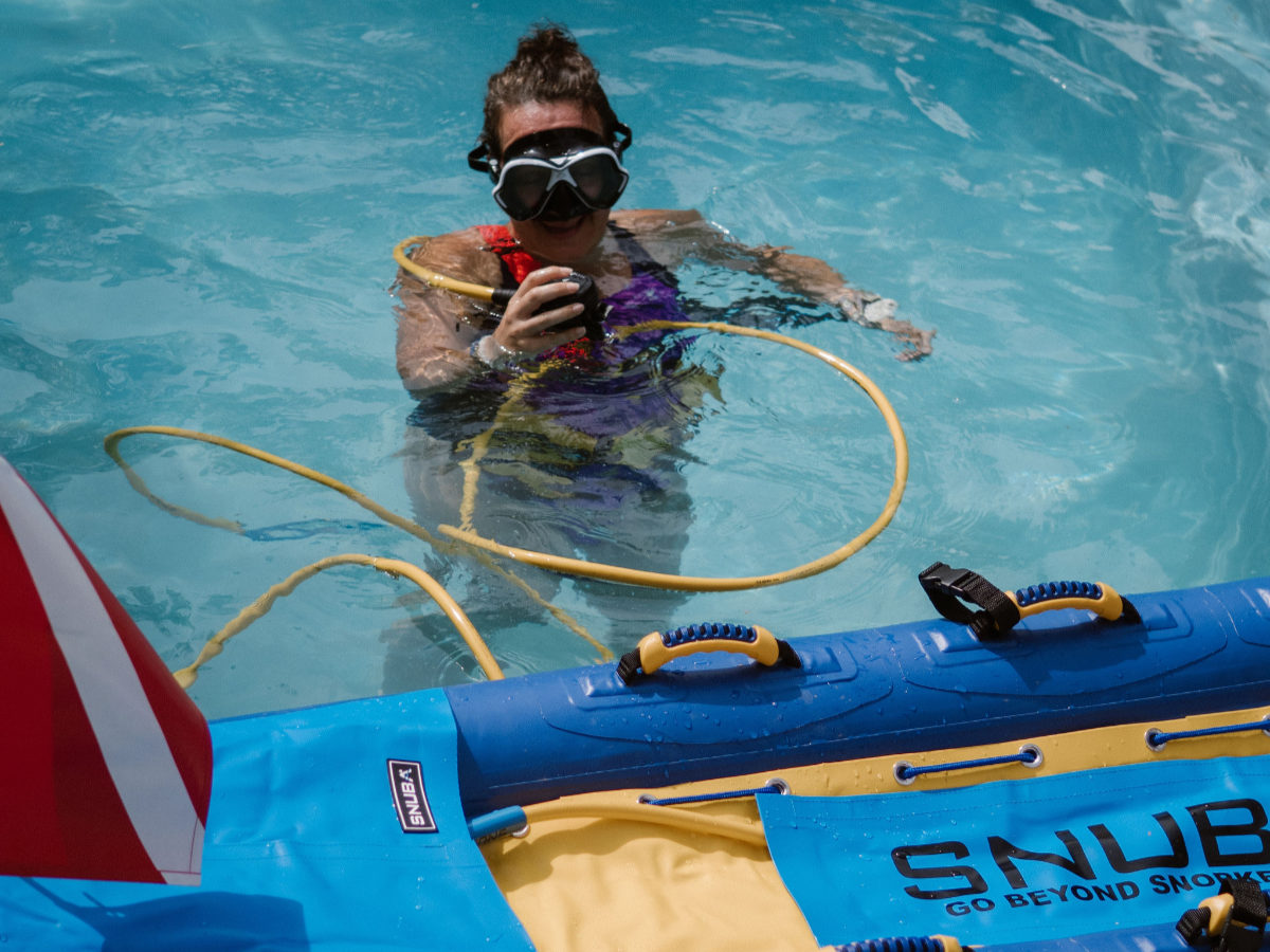 SNUBA Bonaire guest practicing with regulator and floating air raft
